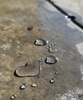 Water droplets forming a heart shape on a sealed concrete surface, illustrating Penetrating Siloxane PD Weather Seal For Concrete, Masonry, Stucco And Manufactured Stone Breathable Water Resistant Shield That Stops Cracking, Spalling, And Stains With 10 Year Service Life, 1 Gallon.