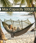Person relaxing in a heavy duty camping hammock with built-in mosquito net and 500 lb capacity, on a beach between palm trees.