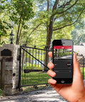 Hand holding smartphone controlling gate with MMS100 Wireless Connectivity System Black for Gate Opener Control From Your Smartphone Anywhere