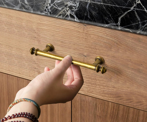 Hand reaching for Six Pack 3 Inch Hole Center Cabinet Pulls Antique Brass Zinc Alloy Drawer Handles for kitchen cabinets