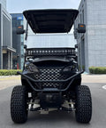 Black 4 Seater Electric Golf Cart With Durable Roof And Clear Windshield Including Front Basket And Rear Cargo Box Engineered For Street Legal Neighborhood Kick Back Cruising front view showing rugged design and large tires.