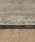 Close-up of one-quarter inch thick Non Slip Rug Pad With Felt And Latex Rubber Gripper on hardwood floor, 6 by 9 feet, Made in USA.