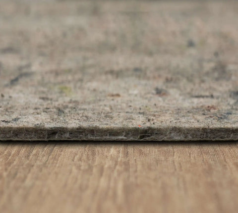 Close-up of one-quarter inch thick Non Slip Rug Pad With Felt And Latex Rubber Gripper on hardwood floor, 6 by 9 feet, Made in USA.