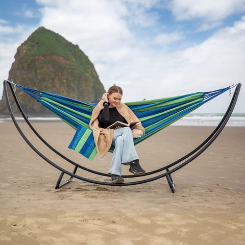 Heavy Duty Hammock Stand With Foldable Frame For Patio Hangout, Blue Green fabric, on beach, accommodates two to three people.