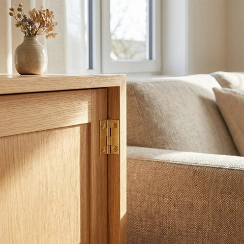 4 Pack 1 Inch Brass Butt Hinges For Wooden Boxes, mounted on a light wood cabinet door next to a beige sofa.
