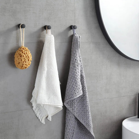 Compact Brass Robe Hook For Bathroom With Glue holding towels and sponge on gray wall, matte black finish