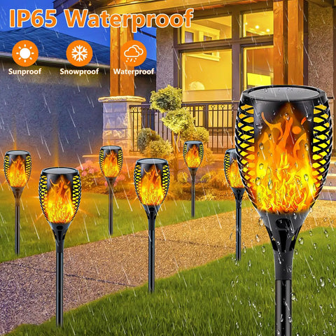 8 Pack Ultra Bright Solar Torch Lights With Flickering Flame installed along a garden pathway, waterproof in rainy weather.