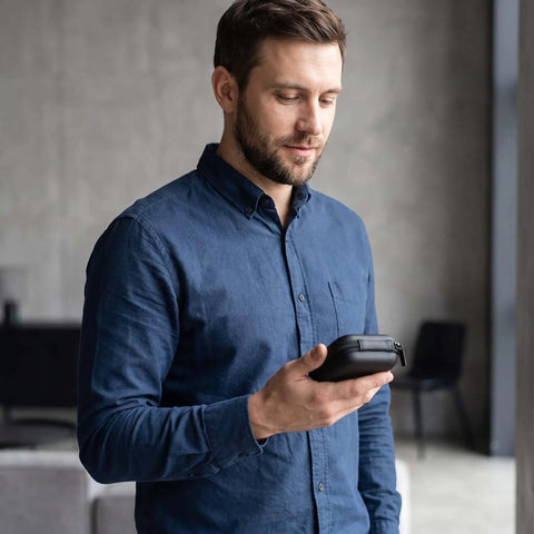 Man holding a Black Hardshell Tech Travel Case For Cables And Chargers With Mesh Pocket And Elastic Straps Drip Proof Eva.