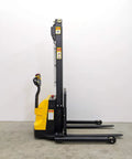 Built Tough Electric Wide Leg Pallet Stacker Heavy Lifter With 2204 Lbs Capacity And 130 Inch Lift Featuring Maintenance Free Battery 110V Us Plug Speed Control And Three Year Warranty Yellow side view showing lifting forks and control handle.