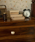 Bedroom nightstand with soft champagne bronze cabinet knob, radio, books, and an alarm clock