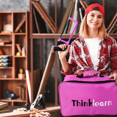 Woman in workshop holding a pink saw and pink carrying case from the Pink 205-Piece Tool Kit For Gals With USB Electric Screwdriver And Drill Adapter.