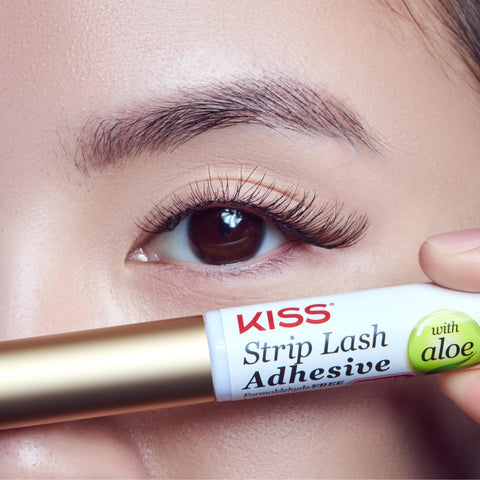 Close-up of eye with strip lashes, holding Clear Lash Adhesive For Strip Lashes And Lash Clusters, Waterproof All Day Hold, Latex Free With Aloe