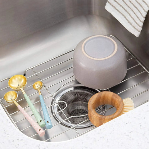 Stainless Steel Sink Protector Grid 12 X 10.25 Inch Rust Resistant Non Slip Kitchen Sink Rack with dishes and utensils on top.
