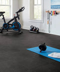 Interlocking Rubber Floor Tiles 18x18 Inch Diamond Plate Squares That Are Tough-As-Nails For Home Gym Garage Basement And Trade Show Floors, Durable Puncture-Resistant Mats, 24 Pack Black shown in gym setting with exercise equipment.