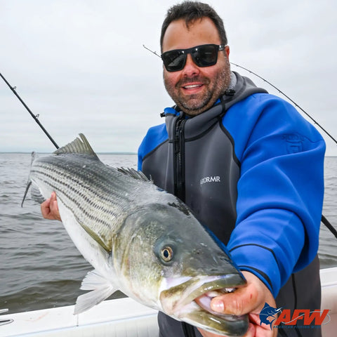 Angler holding a large fish on a boat wearing a blue jacket, showcasing Pro Grade Copper Crimp Sleeves For Fishing Line Single Barrel Size Seven