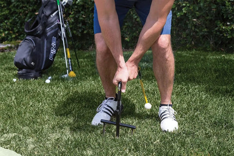 Person using Pure Path Golf Swing Trainer yellow large with ground stakes in backyard, providing swing path feedback without net.