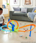 Child playing with Launch And Loop Toy Car Track Set with Cranked Wheel Booster and Figure Eight Crash Zone on living room floor.