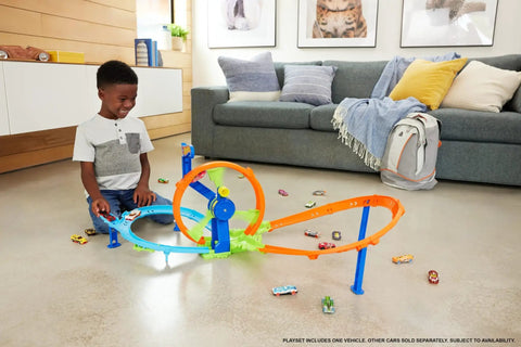 Child playing with Launch And Loop Toy Car Track Set with Cranked Wheel Booster and Figure Eight Crash Zone on living room floor.