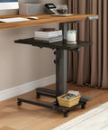 Mobile Adjustable Height Laptop Desk On Wheels Tiltable Work Table beside a wooden desk in a home office setting.