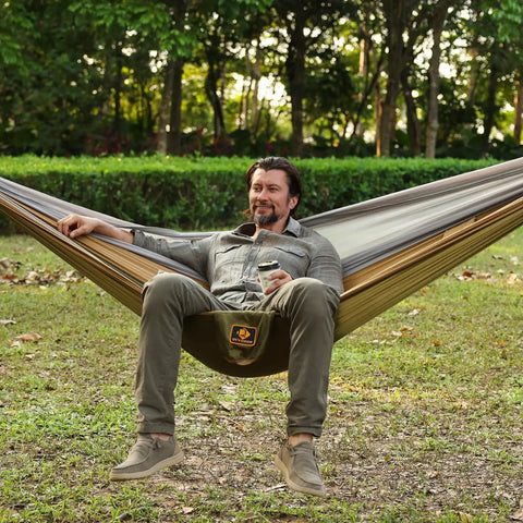 Man relaxing in a Super Comfy Double Hammock With Mosquito Net For Outdoors Portable Lightweight Nylon Parachute Hammock.