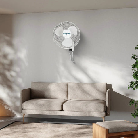 Living room with wall mounted 16-inch oscillating fan above sofa. Two Pack 16 Inch Oscillating Wall Mounted Fans With 90 Degree Wide Oscillation Quiet Operation And Three Speed Settings Indoor Air Cooling For Home Garage Office Shed And Grow Tents With Pull Cord Controls.