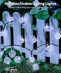 Close-up of 2-Pack 72 Ft Solar String Lights with 120 LEDs illuminating a white fence, showcasing waterproof feature for outdoor use.