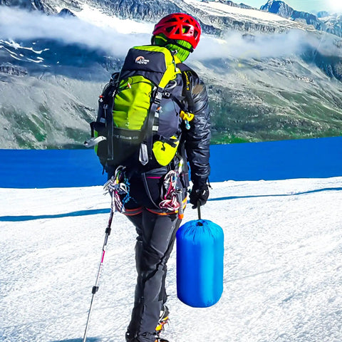 Hiker in snowy mountains carrying Portable Waterproof Sleeping Bag For Adults And Kids, 4 Seasons Cold Weather Or Warm, Ideal For Backpacking.