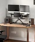 35 Inch Electric Standing Desk Converter With Slick Quiet Lift Height Adjustable Stand Up Riser Dual Monitor And Laptop Setup Wide Keyboard Tray Black Finish on wooden desk, featuring dual monitors and laptop with speakers.