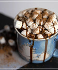 Hot chocolate topped with marshmallows in a blue mug created using 32 Oz Milk Frother And Hot Chocolate Maker With Cocoa Bomb Mold.