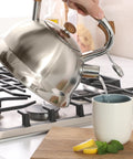 Pouring hot water from Stainless Steel 2 Quart Tea Kettle With Wood Handle For Stovetop Whistling Water Pot into cup