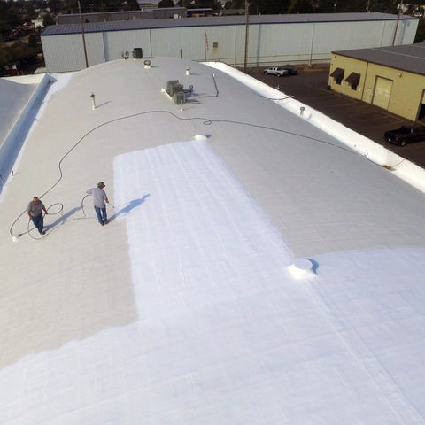 Workers applying Max Stretch Roof Coating White Elastomeric Sealant for Flat and Low Slope Roofs on a large commercial roof