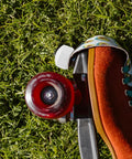 Roller Skate Toe Stoppers And Rubber Toe Guards With Adjustable Brake Blocks And Wrench, side view on grass with red wheel