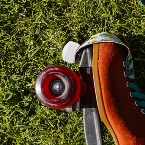 Roller Skate Toe Stoppers And Rubber Toe Guards With Adjustable Brake Blocks And Wrench, side view on grass with red wheel