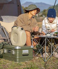 Rugged Folding Storage Box With Lid Heavy Duty Aluminum Frame Stackable Gear Crate Built Tough For Camping And Picnics No Sweat Organization Haul Your Stash On The Go Rust Resistant Silver Design outdoors with campers seated around a table.
