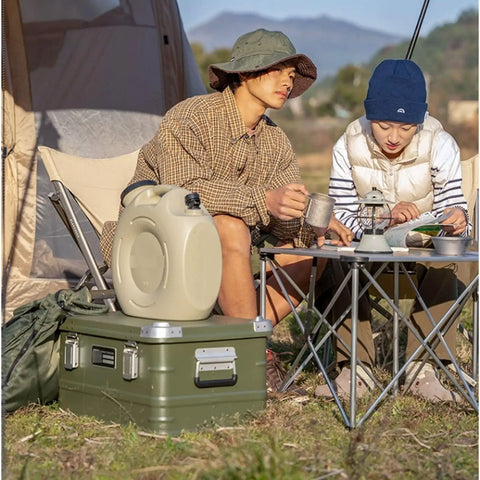 Rugged Folding Storage Box With Lid Heavy Duty Aluminum Frame Stackable Gear Crate Built Tough For Camping And Picnics No Sweat Organization Haul Your Stash On The Go Rust Resistant Silver Design outdoors with campers seated around a table.