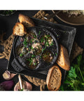 Top view of Cast Iron Escargot Dish With Six Holes, 5.75 Inch, Matte Black, Oven Safe To 500F, Brass Knob, with garnished escargot