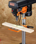 Heavy Duty Benchtop Drill Press Packing A Killer 3.2 Amp Motor And Five Speeds With Ten Inch Swing Plus Tilting Cast Iron Table For Dead On Precision Wood And Metal Drilling, focused on a wood plank.