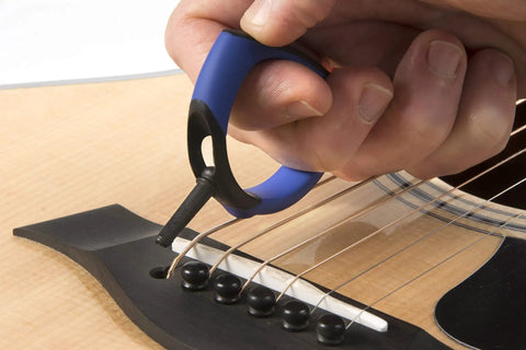 Premium Acoustic Guitar Bridge Pin Puller being used to safely lift a bridge pin on an acoustic guitar.