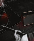 Musician playing guitar with 50 Watt Intelligent Guitar Combo Amp With Amp Intelligence on stage next to drum set
