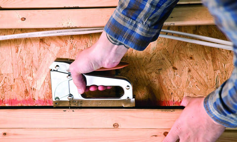 Heavy Duty Staple Gun For Low Voltage Cables And Wires Up To 1/4-Inch Diameter Pro Grade For Alarm Systems in use on wood surface