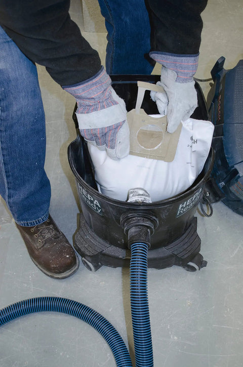 Person placing a VB140F 5 Pack 14 Gallon White Fleece Filter Bag into a dust extractor VAC140.