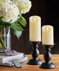 Ivory Scalloped Edge Flameless LED Pillar Candle With Real Wax Look Moving Flame No Mess on black holders beside flowers