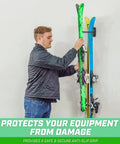 Man placing skis on wall mounted ski and snowboard storage rack for home, garage, or cabin holds 2 pairs of skis or 1 snowboard