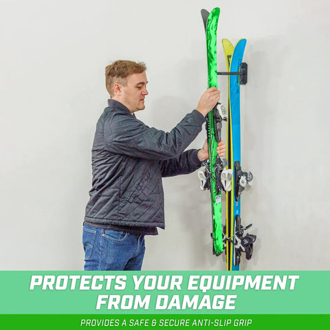 Man placing skis on wall mounted ski and snowboard storage rack for home, garage, or cabin holds 2 pairs of skis or 1 snowboard