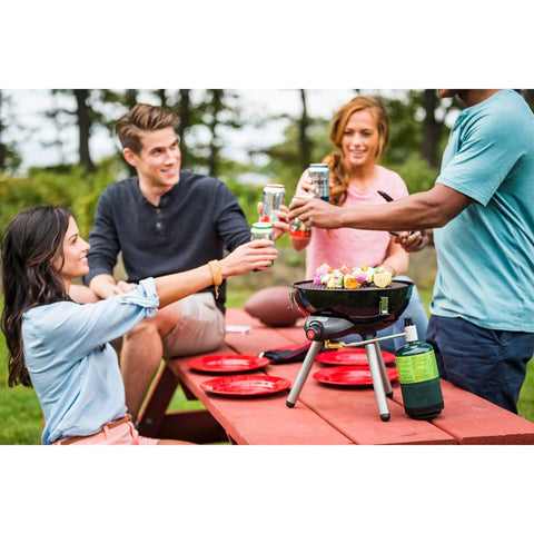 Group enjoying barbecue with red plates and Enamel Dinnerware Set For Outdoor Dining on picnic table outdoors.