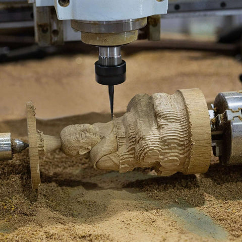 Close-up of a CNC V-bit engraving tool cutting wood on a carved statue; 1/8" shank carbide, 30°.
