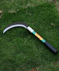 Heavy Duty Weeding Sickle With Manganese Steel Blade And Hardwood Handle Serrated Grass Hook Cutter For Yard Ready Removal Of Unwanted Vines And Weeds In The Garden resting on grass.