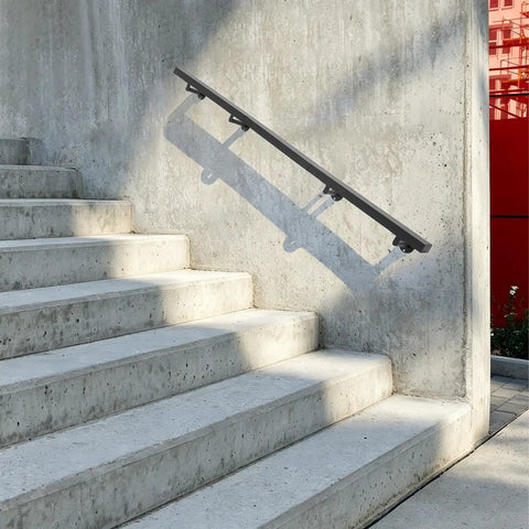 Heavy Duty Stainless Steel Flush Wall Mount Stair Railing secured to concrete stairs, matte black finish, supports two hundred pounds.