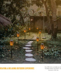 Outdoor Solar Flickering Torch Lights 8 Pack Waterproof Patio Tiki Lamps With 12 LED Flame Beams illuminating a garden path