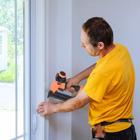 Lightweight 18 Gauge Pneumatic Brad Nailer For Cabinetry And Finish Work in use on window trim, quick jam release, orange handle